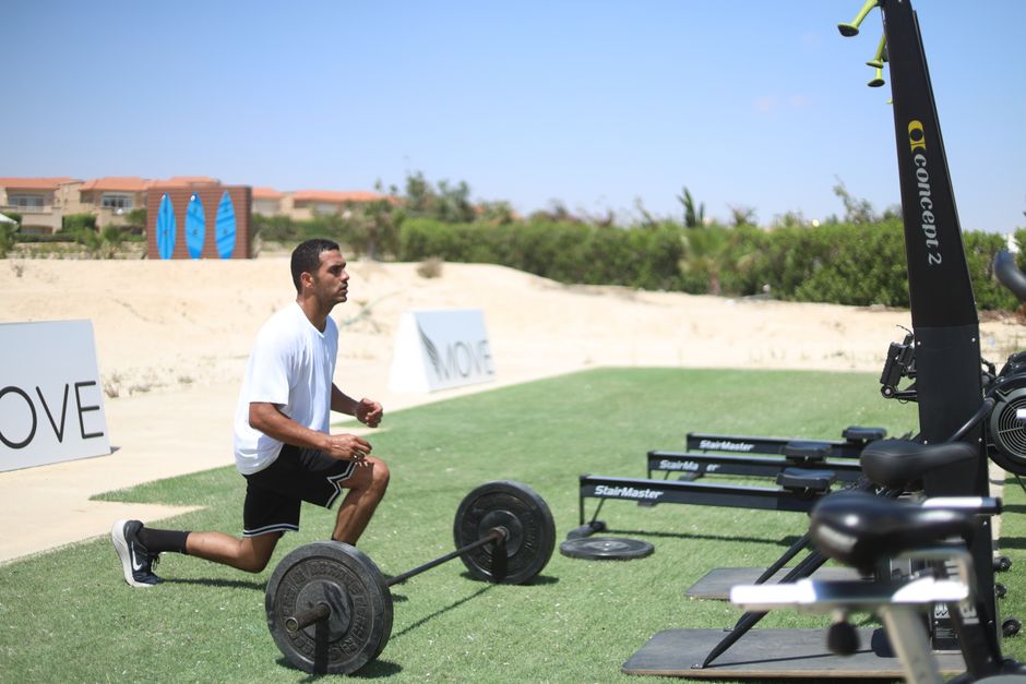 Man working out with barbell outdoors, focusing on dynamic fitness and strength.