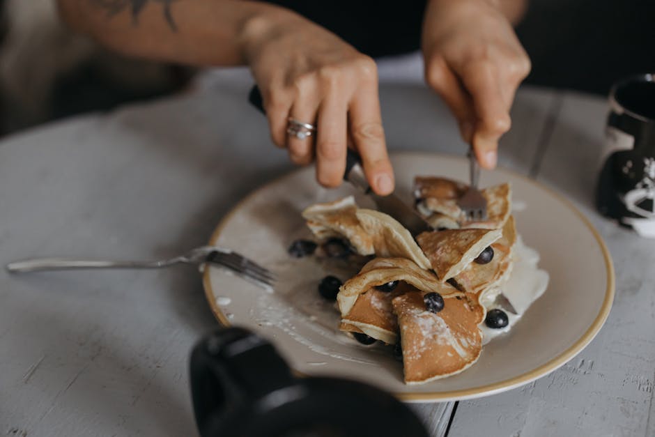 A tempting breakfast featuring pancakes topped with blueberries and cream.