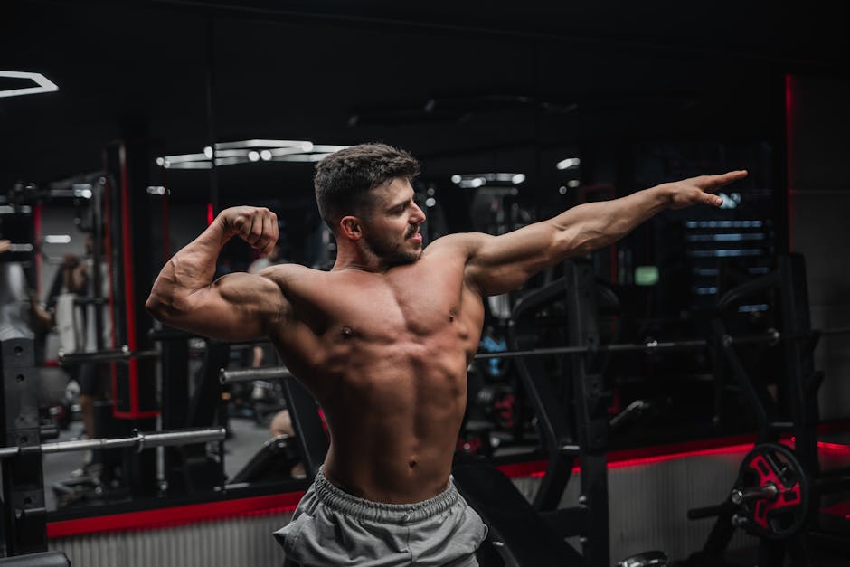 Strong shirtless man flexing muscles in a gym, showcasing fitness and determination.