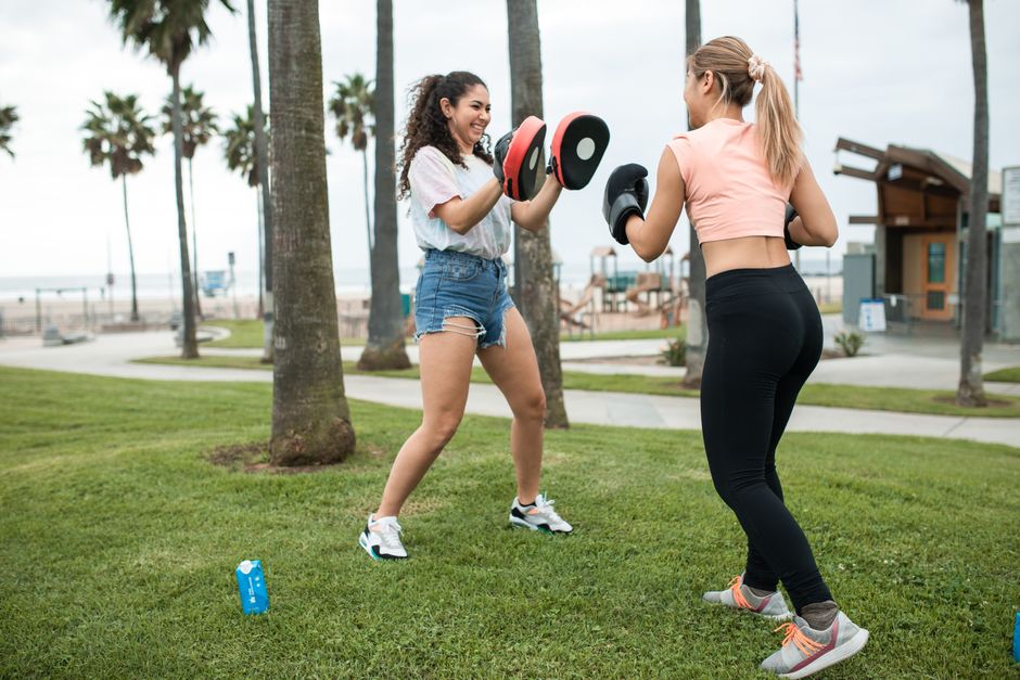 Two women engaging in a dynamic boxing workout session outdoors, enjoying fitness training.
