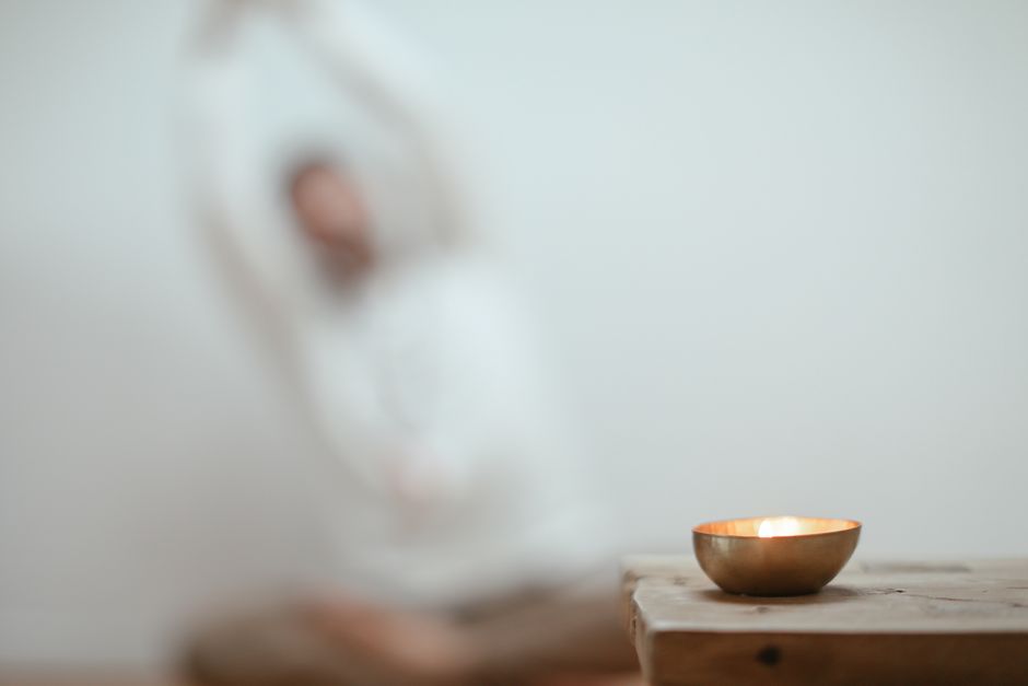 Calm scene with a singing bowl and blurred yoga pose, promoting tranquility.