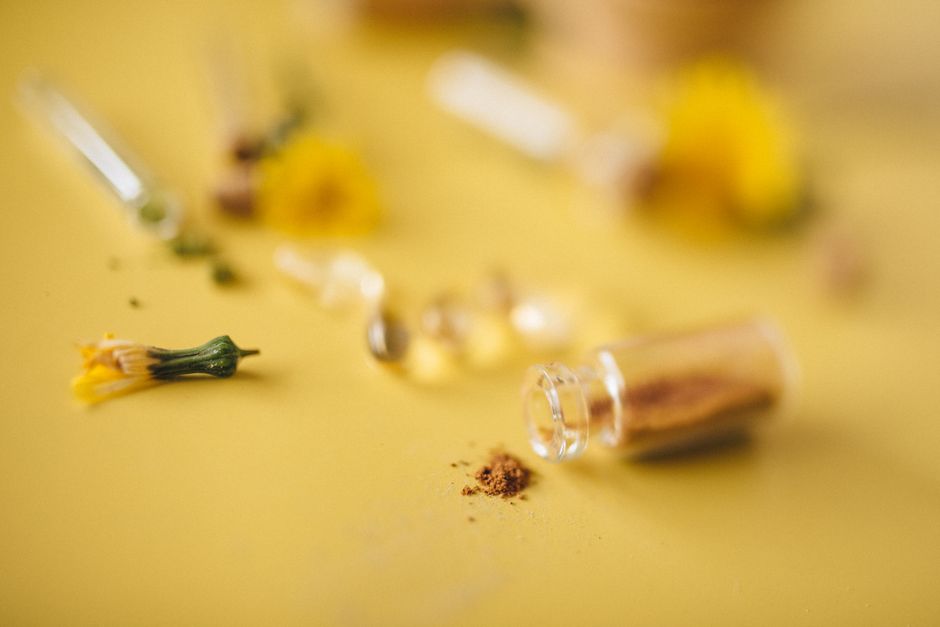 Close-up of herbal powder and flowers on a yellow surface, concept of natural remedies.