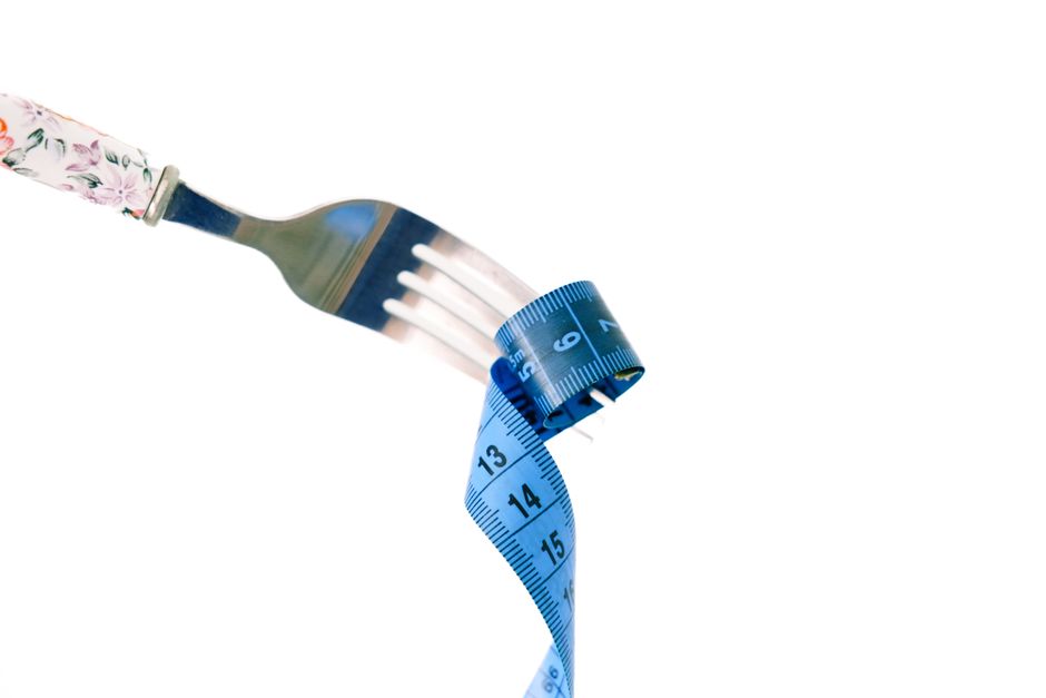 A fork twirls a blue measuring tape, symbolizing weight management and health.