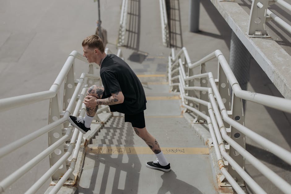 Man warming up on concrete stairs for outdoor workout, wearing black athletic clothing.