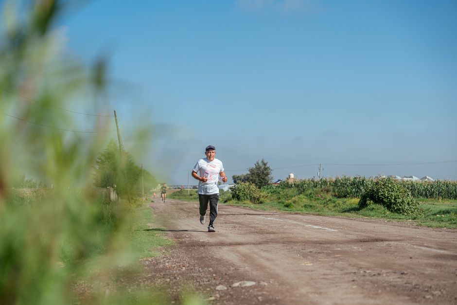 Adult man jogging on a rural dirt road, showcasing outdoor fitness and health in a peaceful countryside.