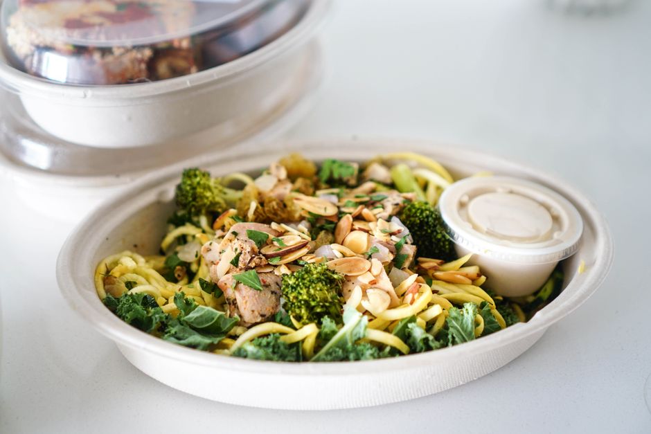 A fresh takeout salad with broccoli, almonds, and dressing, perfect for a healthy meal.
