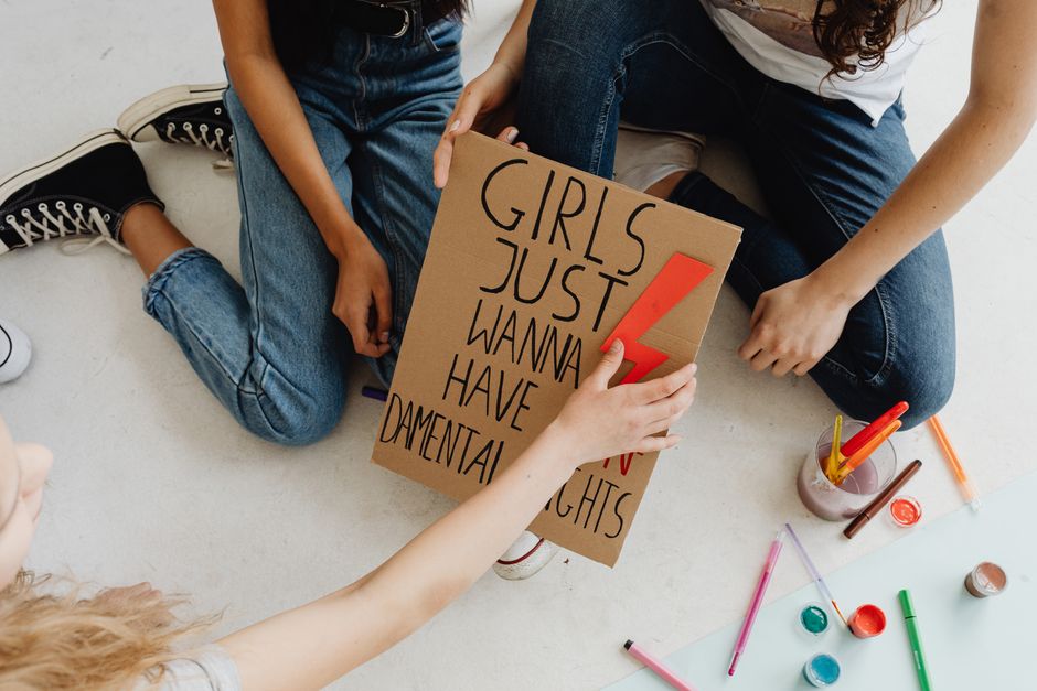 A group of young women creating protest signs with art materials, promoting activism and female empowerment.