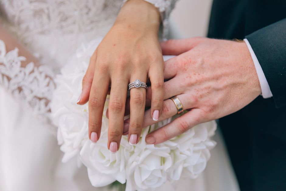 Close-up of bridal and groom's hands with wedding rings, showcasing romance and commitment.