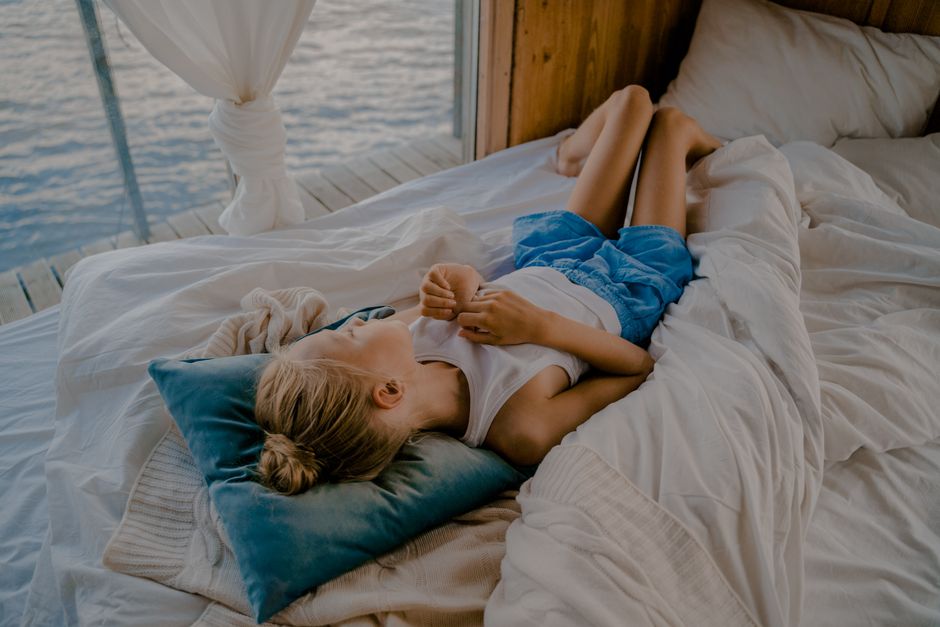 Young girl relaxing on a bed by the lake, enjoying a serene lakeside view.
