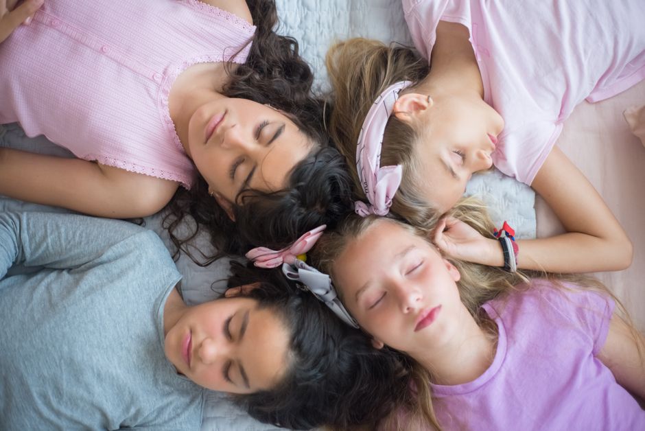 Four girls sleeping peacefully during a fun sleepover, showcasing friendship and relaxation.