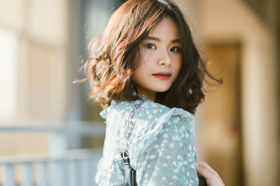 Elegant portrait of an Asian woman wearing a floral dress outdoors.