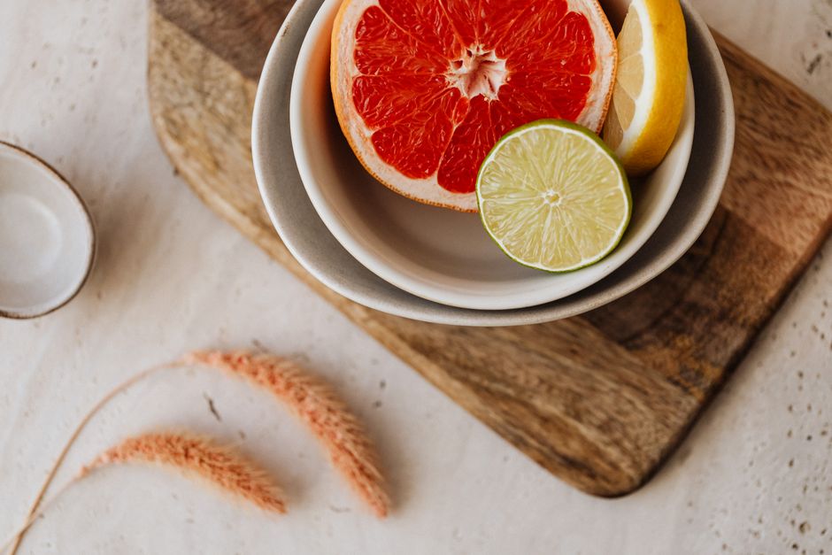 Fresh sliced grapefruit, lemon, and lime in bowls on a wooden board. Ideal for food visuals.