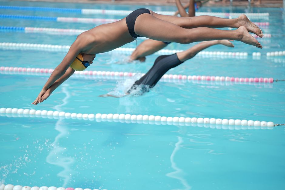 Young athletes diving into a clear pool during a competitive swimming event.