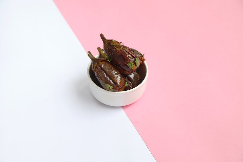 Delicious Indian stuffed eggplants in a white bowl on a pink and white background, perfect for culinary blogs.