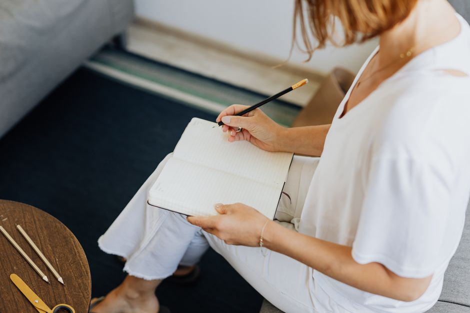 Woman writing health goals in a notebook at home